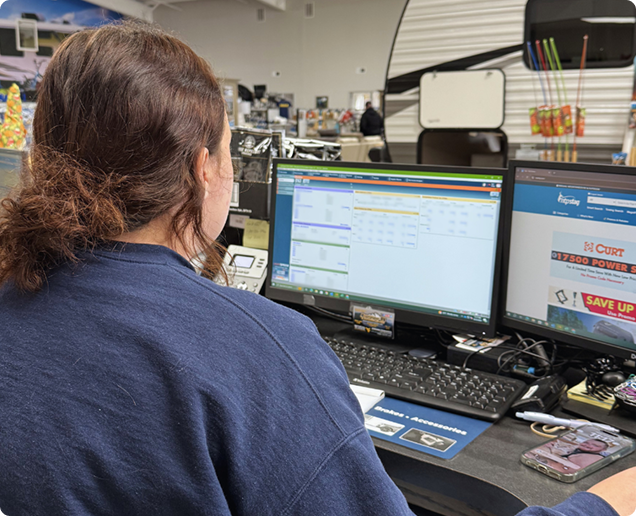 Image of an employee sitting at a desk in front of two computer monitors and a keyboard. Image of an employee sitting at a desk in front of two computer monitors and a keyboard.